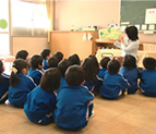 Children listening as their teacher reads from a donated book (Fukuchiyama)